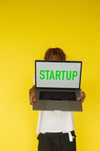 Yellow background and a laptop screen that reads STARTUP - Starting your own business